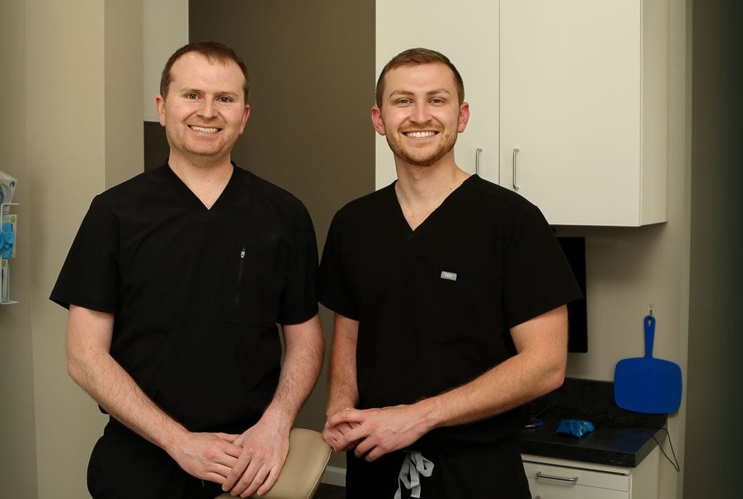 Dr. Nathan Corn and Dr. Derek Corn in scrubs, standing together in a treatment room